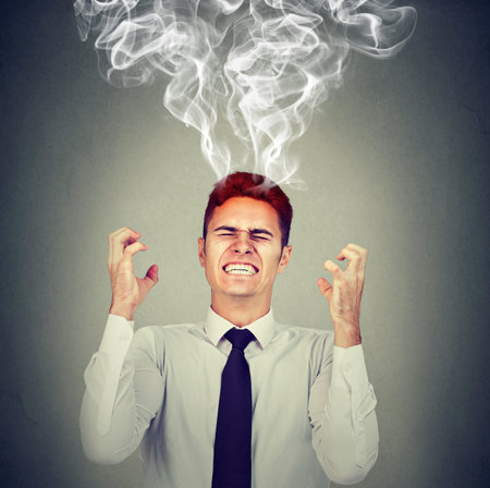 Stressed business man having headache steam coming up isolated on gray wall background