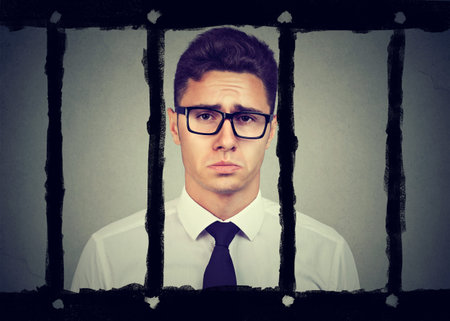 Sad young business man in prisonの写真素材