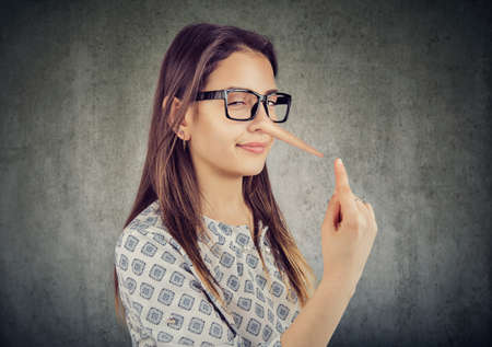 Sly tricky young woman with long nose. Liar concept.の写真素材