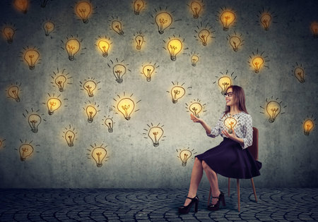 Young pretty business woman juggling with light bulbsの写真素材