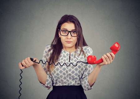 Confused young woman with bad news on the phoneの写真素材