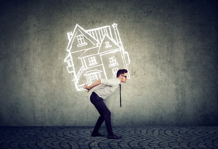 Overburdened business man carrying a house on his back