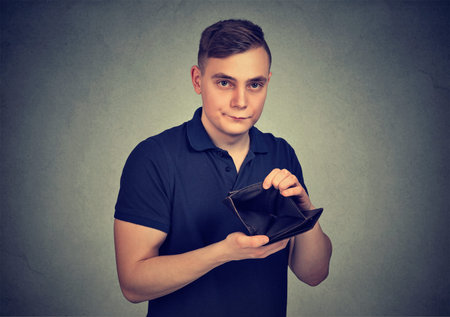 Young man showing empty wallet having no money and looking upset at camera