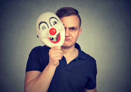 A little mad. Young negative man hiding real face with clown mask having split personality.の写真素材