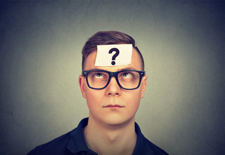 thinking man with question mark on gray wall background