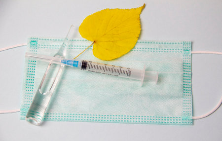 syringe, ampoule medical mask and dry autumn leaves on a white background medicine fall, coldsの写真素材