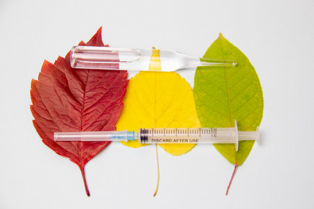 syringe, ampoule and dry autumn leaves on a white background medicine fall, coldsの写真素材