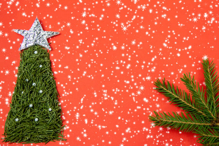 christmas red background, fir tree of pine needles with a silver star on a red background with sparkles, copy space, top viewの写真素材