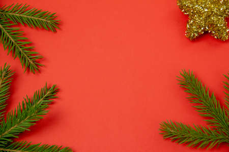 christmas red background, coniferous branch with christmas tree toy, copy space, top viewの写真素材