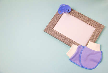 Photo frame and booties on a blue background. Waiting for a baby, motherhoodの写真素材