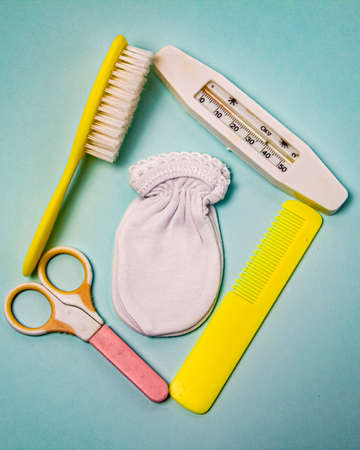 baby combs, thermometer, baby scissors and booties on a blue background.の写真素材