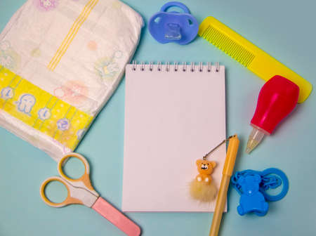diaper, pacifier, comb, scissors and a notepad with a pen to write down the necessary items when the baby arrivesの写真素材