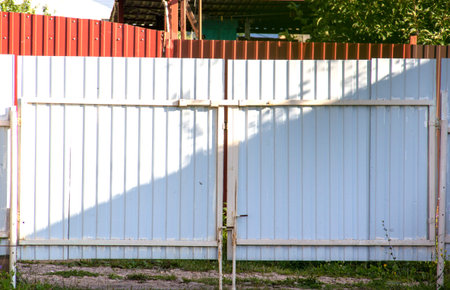 Iron silver rusty fence with earth reinforcement gate. simple old fence in a country house dacha