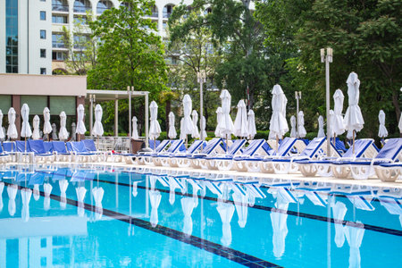 Swimming pool with empty loungers and closed umbrellas at luxury hotel . high quality photoのeditorial素材