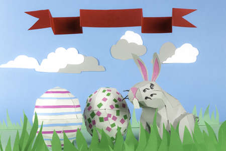 Rabbit made of paper in a happy paper environment and a ribbon with space for textの写真素材