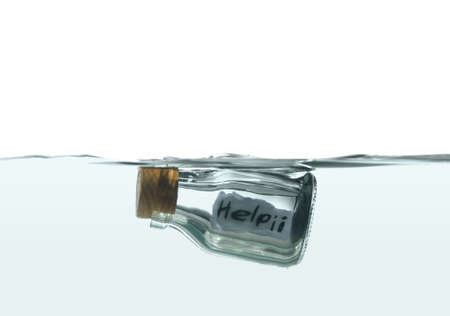 Bottle floating on water with a mayday message insideの写真素材