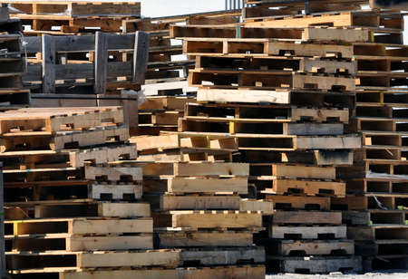 Piles of stacked wood pallets outside of warehouse.の写真素材