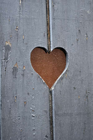 Heart-shaped cut on old wooden door.の写真素材