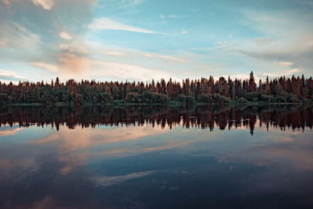 Forest river Bank at sunset with reflection in the waterの写真素材
