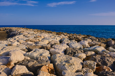boy standing on the rocks above the mediterranean sea in pedregalejo, malaga