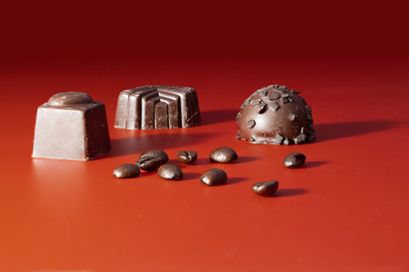 chocolate candies on a red background with coffee beans, top view