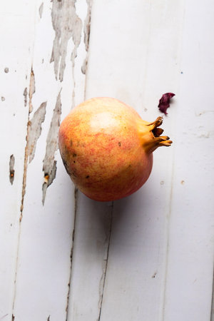 Ripe pomegranate fruit on a white wooden background.