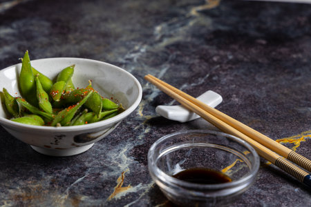 Green soybean in bowl with chopsticks and soy sauce on dark backgroundの写真素材