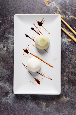 Japanese rice ball with ice cream and chocolate sauce on a white plateの写真素材