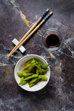 Green soybeans with soy sauce and chopsticks on a stone backgroundの写真素材