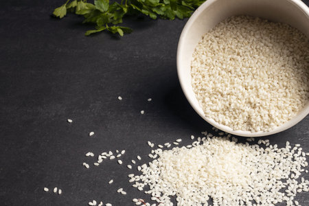 Raw rice in a bowl on a slate background. Selective focus.の写真素材
