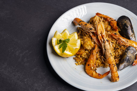 Seafood paella with shrimps, mussels, squid and prawns served on a plate with lemonの写真素材
