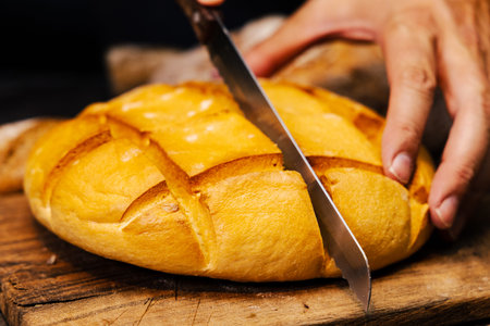 Freshly baked loaf of bread on a wooden board with a knife
