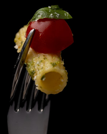 italian pasta with tomato and basil on a fork on a black backgroundの写真素材