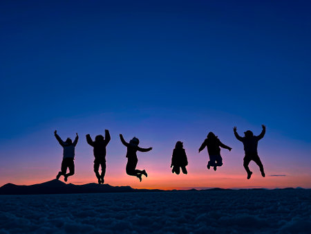 six friends jumping with bluish skyline at sunsetの写真素材