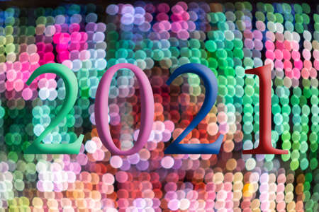 Text with the year number 2021 with a background of bright out of focus lights in various shades with Bokeh effect. Happy New Year 2021.の写真素材