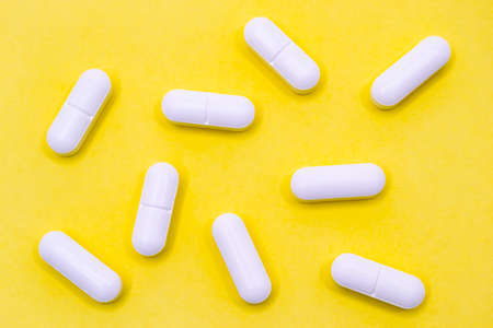 Set of white pills on a yellow background. Horizontal photography.の写真素材