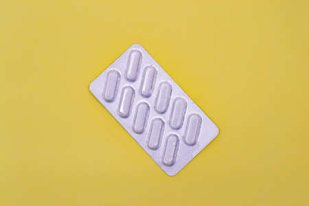 Pack of white pills on a yellow background. Horizontal photography.の写真素材