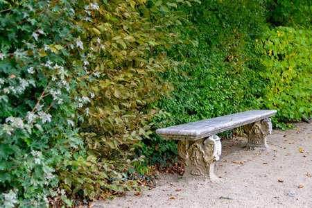 Stone and marble bench with a background of green leaves from a bush in a park and garden in Segovia, in Spain. Europe. Horizontal photographyの写真素材