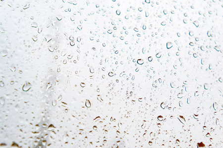 Raindrops on a window pane with a cloudy, rainy day and gray clouds, in Madrid, Spain. Europe....