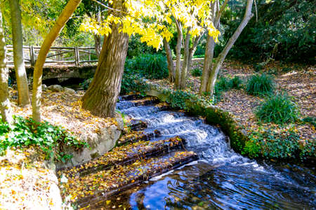 River-stream passing through Parque del Oeste, Madrid park with some autumn colors on a clear day in Madrid, Spain. Europe. Photograph.の写真素材