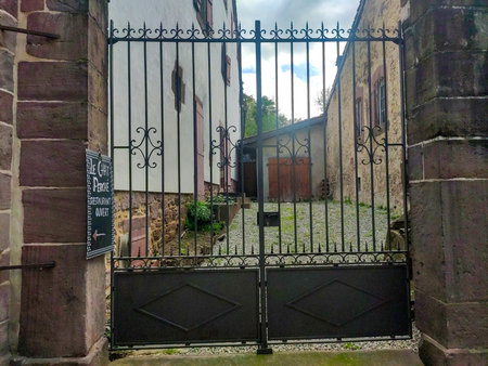 Iron fence that is a door in a French street surrounded by a rocky wall and with stones. Horizontal...