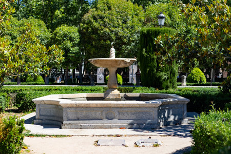Fountain. Stone fountain surrounded by green vegetation in a park in Madrid on a clear day with a...