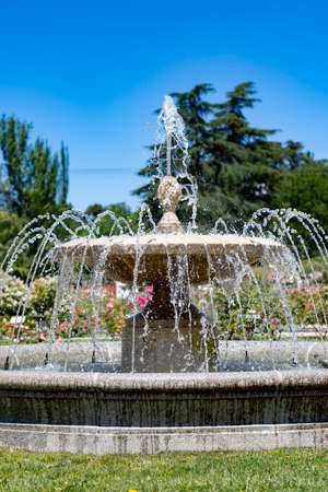 Fountain. Stone fountain filled with water with an explosion of spring with colorful flowers in the entire park of Madrid on a clear day and with a blue sky, in Spain. Europe. Photography.の写真素材