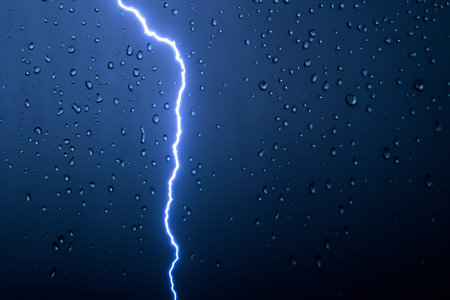 Rain. lightning. Raindrops on the window. Rainy day. Blue tone. Background with lightning. Macro...