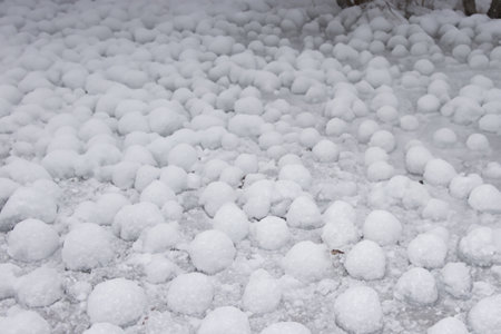 Hail. Thai dessert, glutinous rice balls, closeup of photo. Frozen melon leaves with snow in winter season. Close up of woman hands holding ice cubes. Focus on foreground.の写真素材