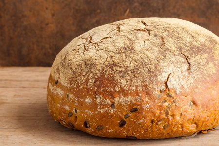 Bread. Close up of rustic bread loaf on wooden table. Baker or chef holding fresh made bread....