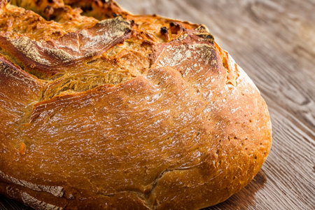 Bread. Close up of rustic bread loaf on wooden table. Baker or chef holding fresh made bread....