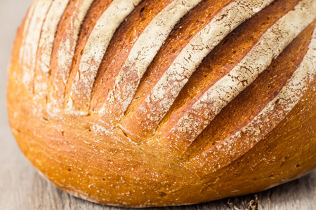 Bread. Close up of rustic bread loaf on wooden table. Baker or chef holding fresh made bread....