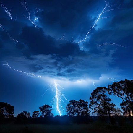 Lightning. Lightning strike. Spectacular night view of a lightning bolt streaking across the dark blue sky. Lightning and thunder and flashes. Clouds and silhouettes of treesの写真素材