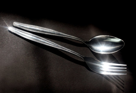 Close up shot of spoon and fork isolated on black background